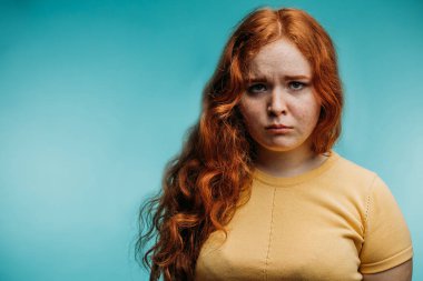 Yüzünde negatif insan ifadesi olan kızıl saçlı kadın..