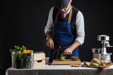 Biftek, salata ve sebzeli yeşil burger pişiren adam..