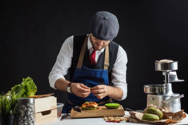 Biftek, salata ve sebzeli yeşil burger pişiren adam..