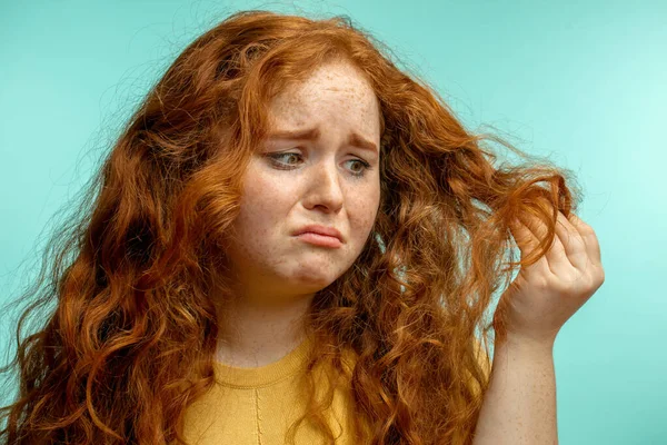 Sconvolto e donna con i suoi capelli secchi danneggiati espressione del viso sfondo blu — Foto Stock