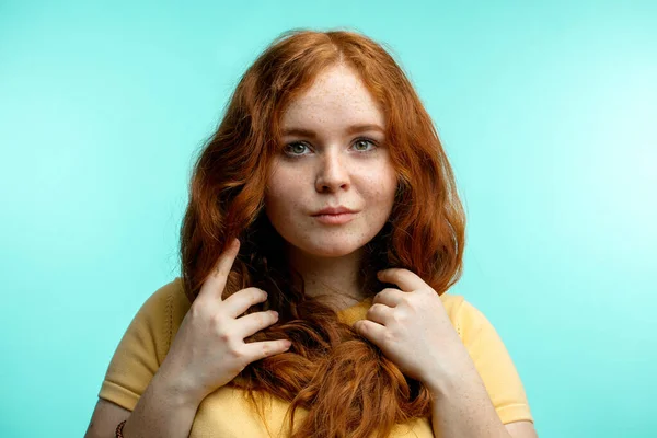 Redhead girl with curly hair crossed smiling looking at camera over blue background — Stock Photo, Image