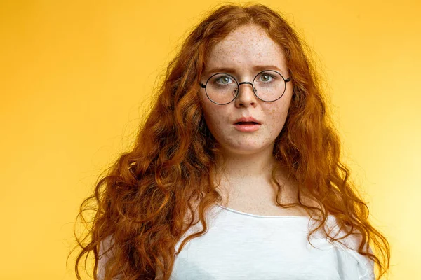 Genç, komik, kızıl saçlı bir kadın şok olmuş bir ifadeyle kameraya bakıyor.