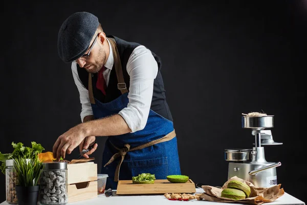 Biftek, salata ve sebzeli yeşil burger pişiren adam..