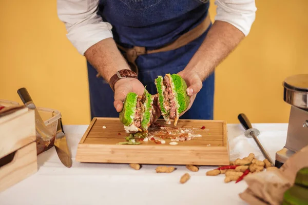 Chef cięcia burger na dwie połówki, aby wykonać wysokiej jakości składniki — Zdjęcie stockowe