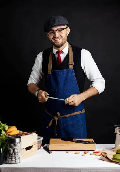 상업용 주방에서 한 남성 요리사가 칼을 날카롭게 자르고 있는 모습 — 스톡 사진