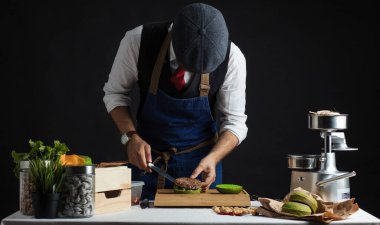 Biftek, salata ve sebzeli yeşil burger pişiren adam..