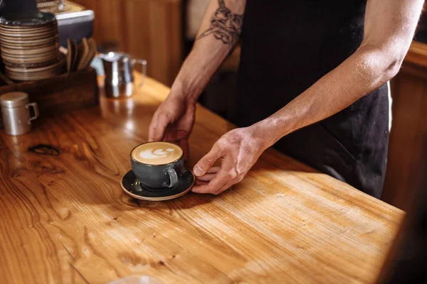Kellner hält eine Tasse Caffe Latte in der Hand — Stockfoto