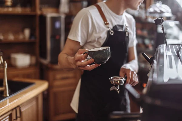 Barista hält Tasse und Stampfer mit gemahlenem Kaffee in der Hand — Stockfoto