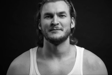 Uzun saçlı, traşsız bir adamın siyah ve beyaz pozu.