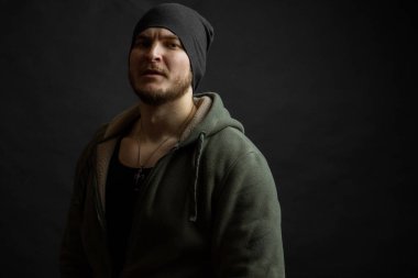 Şapka takan yakışıklı bir adam. atlet, kapüşonlu ve kolyeli.