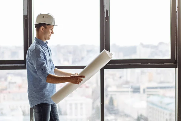 Ung trevlig arkitekt håller ritning en i kontorsrenovering — Stockfoto