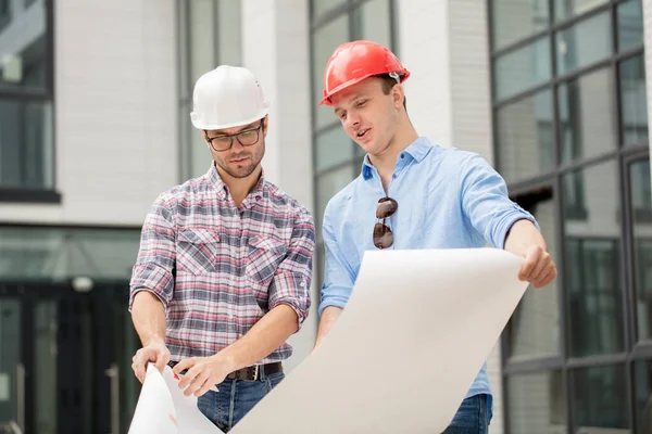 Zwei Bauarbeiter blicken durch das Diagramm — Stockfoto