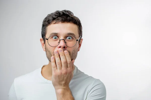 Un uomo emotivo con gli occhi spiati sta chiudendo la bocca con la mano — Foto Stock