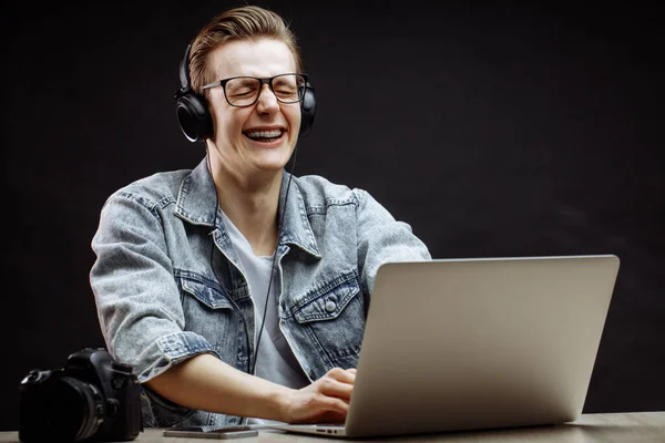 Jong mannelijk model is lachen met gesloten ogen tijdens het typen op de notebook — Stockfoto