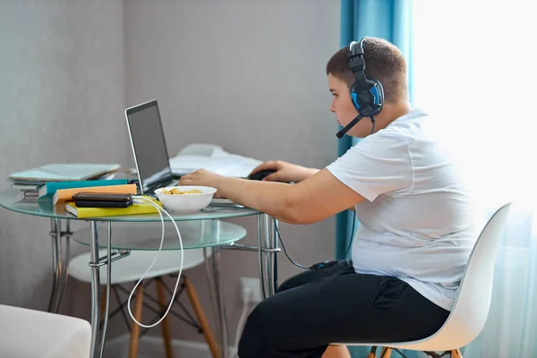 fat teenager boy eat junk food and play computer games