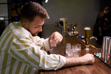 Sarhoş genç adam barda oturuyor.