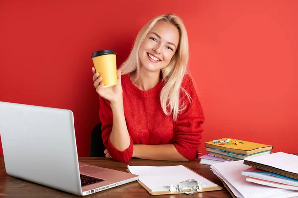 Молодая женщина пить кофе во время работы на ноутбуке — стоковое фото
