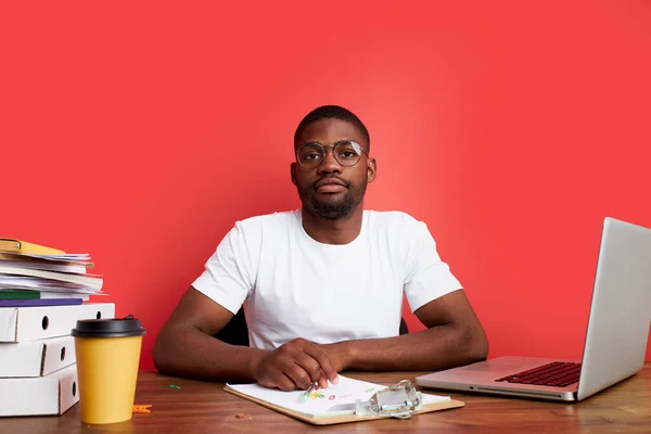 Excesso de trabalho infeliz e frustrado jovem africano em estresse sentado na mesa de escritório — Fotografia de Stock