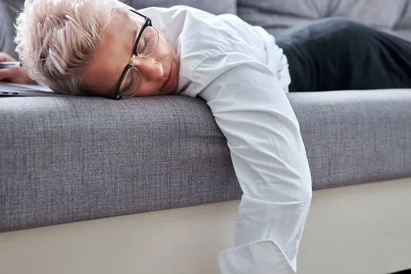 Profesor cansado está durmiendo en el sofá durante la lección en línea —  Fotos de Stock