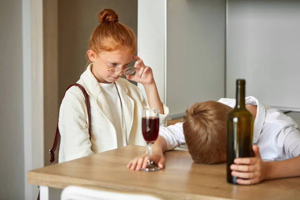 Niños pequeños pareja en casa, chico está bebiendo alcohol —  Fotos de Stock