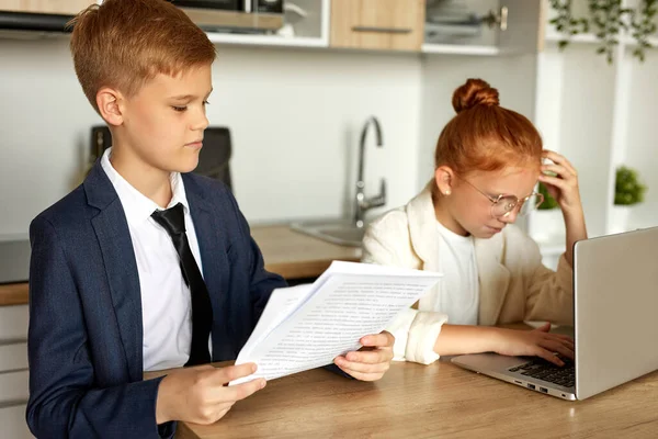 Niños caucásicos entraron en el papel de adultos, trabajar en el ordenador portátil con documentos — Foto de Stock