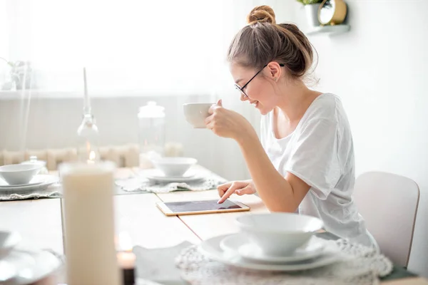 Side view photo of an attractive girl surfing the net in the kitchen — Stock Photo, Image