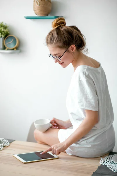 Young nice woman sitting on the table and using digital tablet — Stock Photo, Image