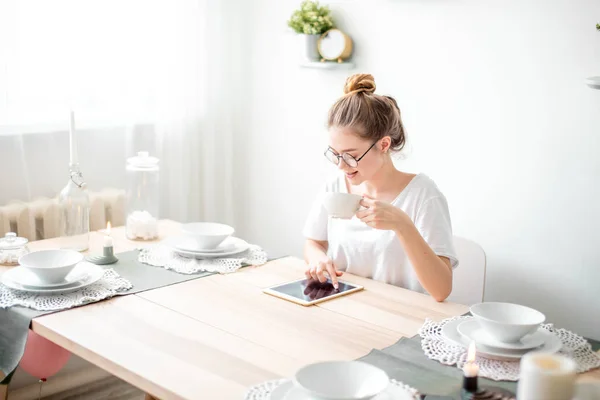 A beautiful girl using a digital tablet in the kitchen — Stock Photo, Image