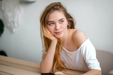 Romantik kız eline yaslanırken akıllı bir telefon tutuyor.