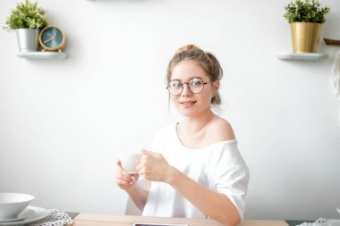Harika bir genç kadın mutfakta bir fincan çay ve modern bir iç mekan..