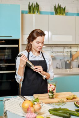 Genç yetenekli şef mutfakta yemek pişirirken mikseri kullanıyor.