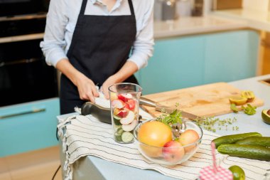 Genç bir kadın meyve suyu yapmak için gerekli malzemeleri hazırladıktan sonra ellerini siliyor.