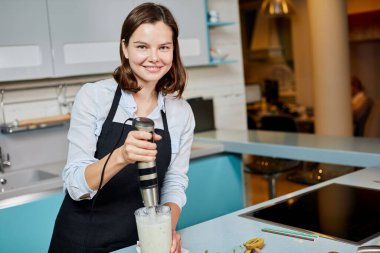 Milkshake sevgiyle hazırlanıyor. pozitif ev hanımı meyve suyu yapıyor