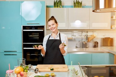 Pozitif harika kız elinde kesilmiş avokadoyu tutuyor.