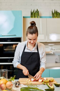 Harika bir genç kadın mutfakta pasta süslemesi için elma kesiyor.