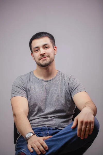 Portret van een jonge sterke man met positieve uitdrukking zittend op een stoel — Stockfoto