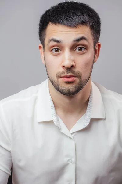 Ein überraschter junger Mann im weißen Hemd blickt in die Kamera — Stockfoto