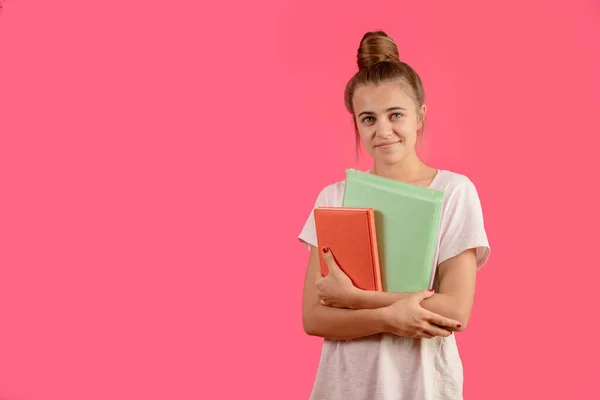 Retrato de joven estudiante con moño de pelo está sosteniendo carpeta verde y cuaderno — Foto de Stock