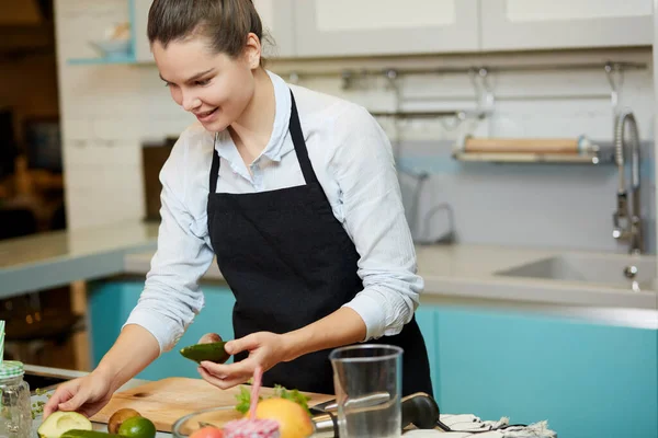 Kvinna matlagning något med avokado i köket rum hemma — Stockfoto