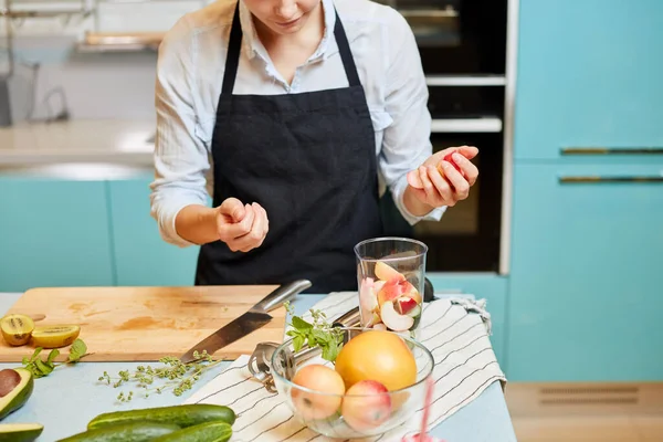 Heureuse femme au foyer ajoutant des pommes à son smoothie fraîchement fait — Photo