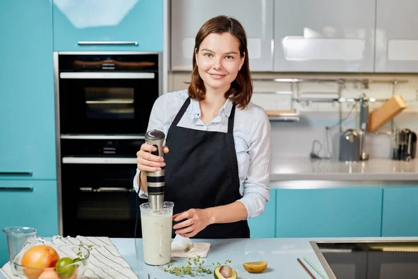 Positief mooi meisje leren voor te bereiden milkshake — Stockfoto