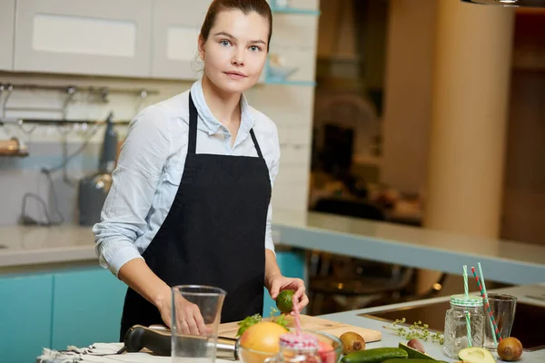 Impresionante chef femenino está mirando a la cámara mientras prepara una comida —  Fotos de Stock