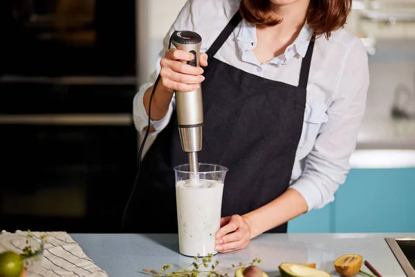 Giovane donna di bell'aspetto sta facendo uno yogurt con frullatore — Foto Stock