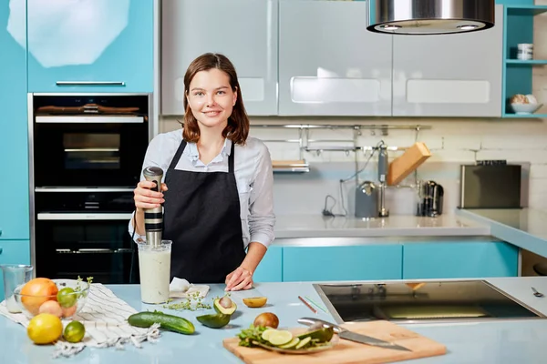 Pozitív női szakács turmixgéppel a kamerába nézve — Stock Fotó