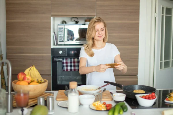 Mutfakta fotoğraf çeken açık renk saçlı genç bir kadının portresini kapat..