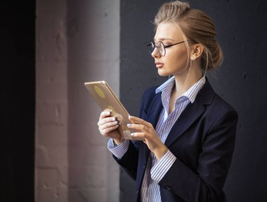 Bayan ofis çalışanı tabletteki fotoğraflara bakıyor.