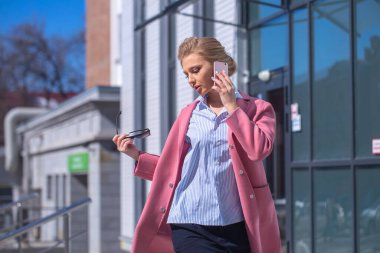 Sarışın kadın akıllı telefondan arıyor.