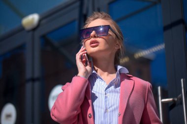 Düşünceli şehirli kadın telefonda arkadaşlarıyla konuşuyor.