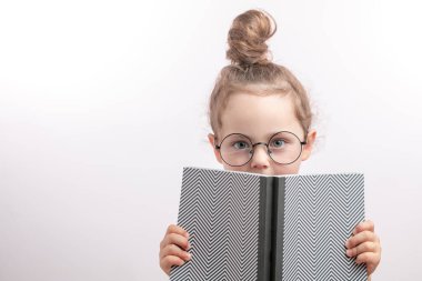 Tatlı kızıl çocuk elinde defterle saklambaç oynuyor.