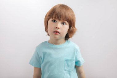 üzgün, mutsuz, ciddi bir çocuk kameraya bakıyor.